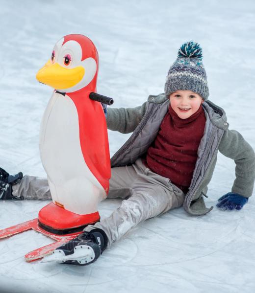 a boy in a coat learns to skate on ice skates